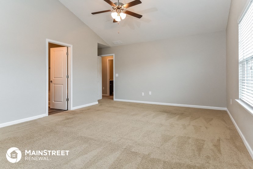 the spacious living room with ceiling fan and carpeting