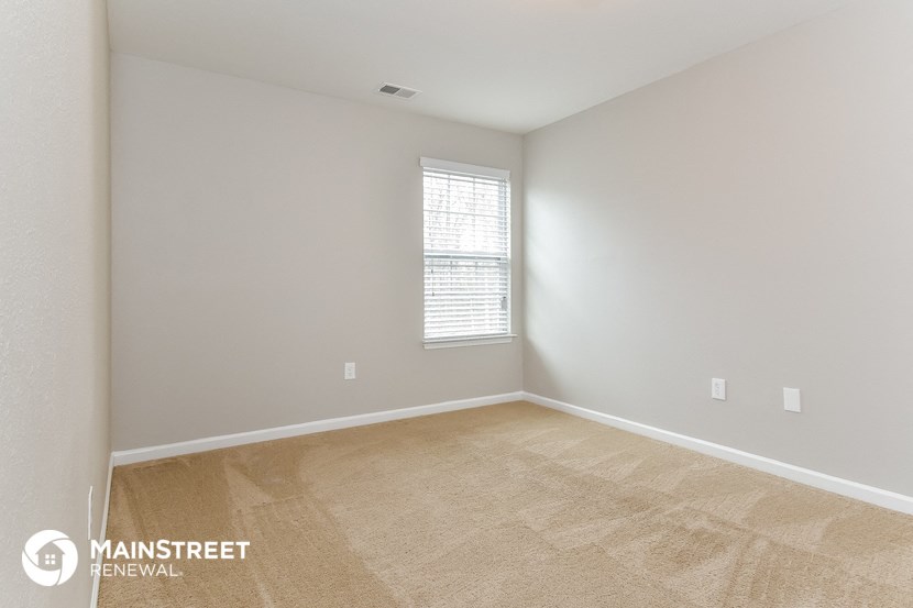 the spacious living room with carpeting and a window