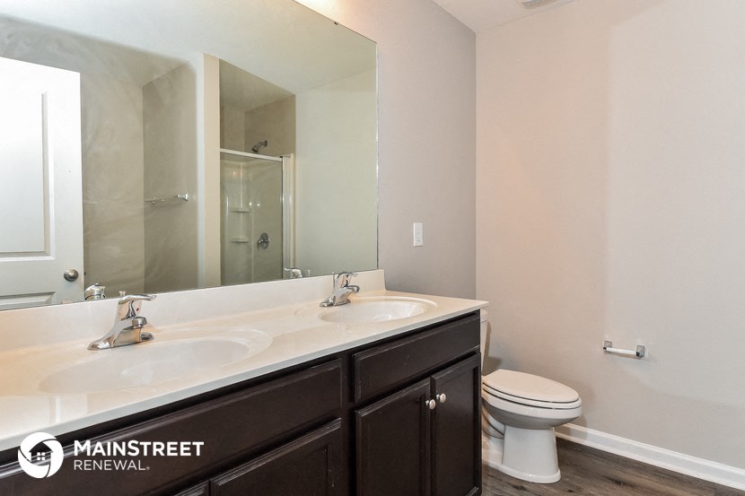 a bathroom with two sinks and a toilet and a large mirror