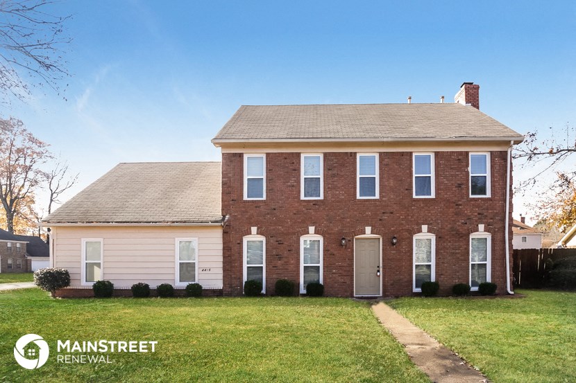 a brick house with a grassy yard and a blue sky