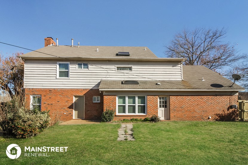 a white house with a brick side yard and a lawn