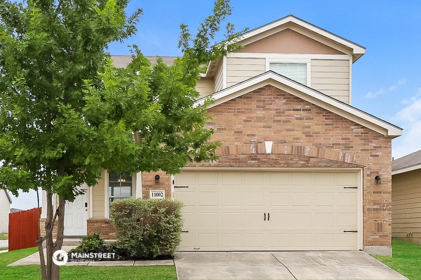 a tan house with a garage door and a tree