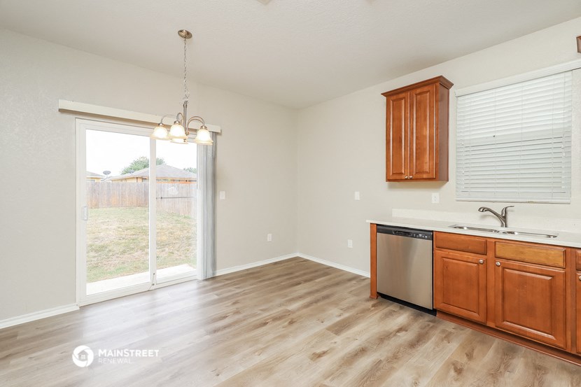 the kitchen and living room of a house with wood floors and a sliding glass door
