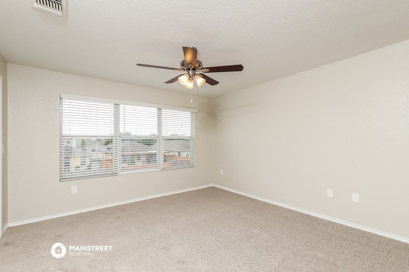 the spacious living room with ceiling fan and large window