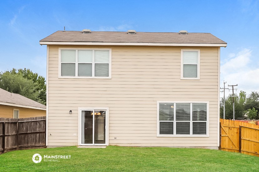 the exterior of a tan house with a yard and a wooden fence