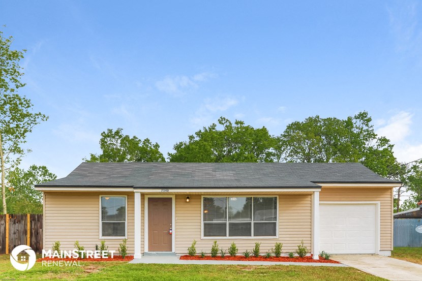 front view of a tan house with a lawn and trees