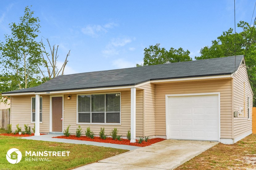 a small tan house with a white garage door