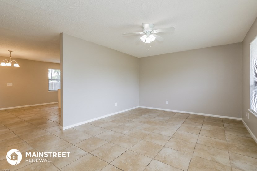 the spacious living room with ceiling fan and tile flooring