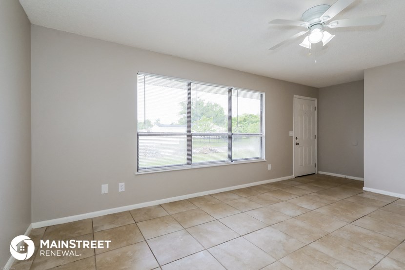 the spacious living room with large windows and tiled floors