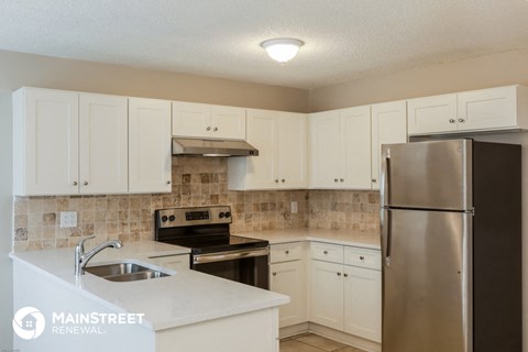 a kitchen with white cabinets and a stainless steel refrigerator