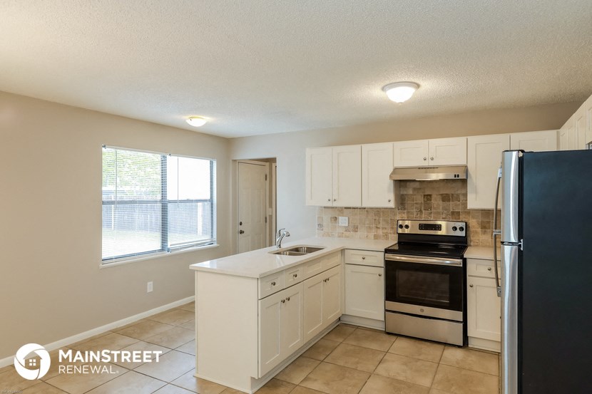 a kitchen with white cabinets and a black refrigerator and a sink