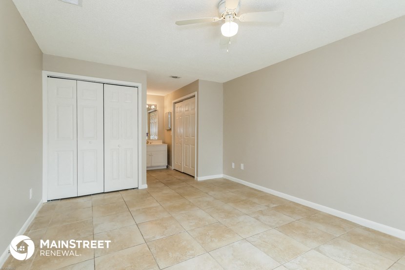the living room is spacious with tile flooring and a ceiling fan