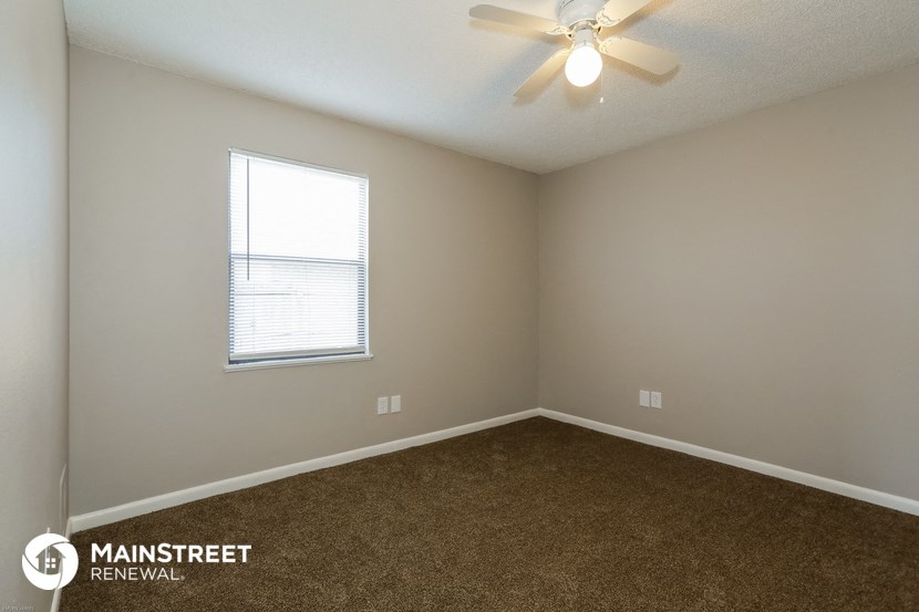 an empty room with carpet and a ceiling fan
