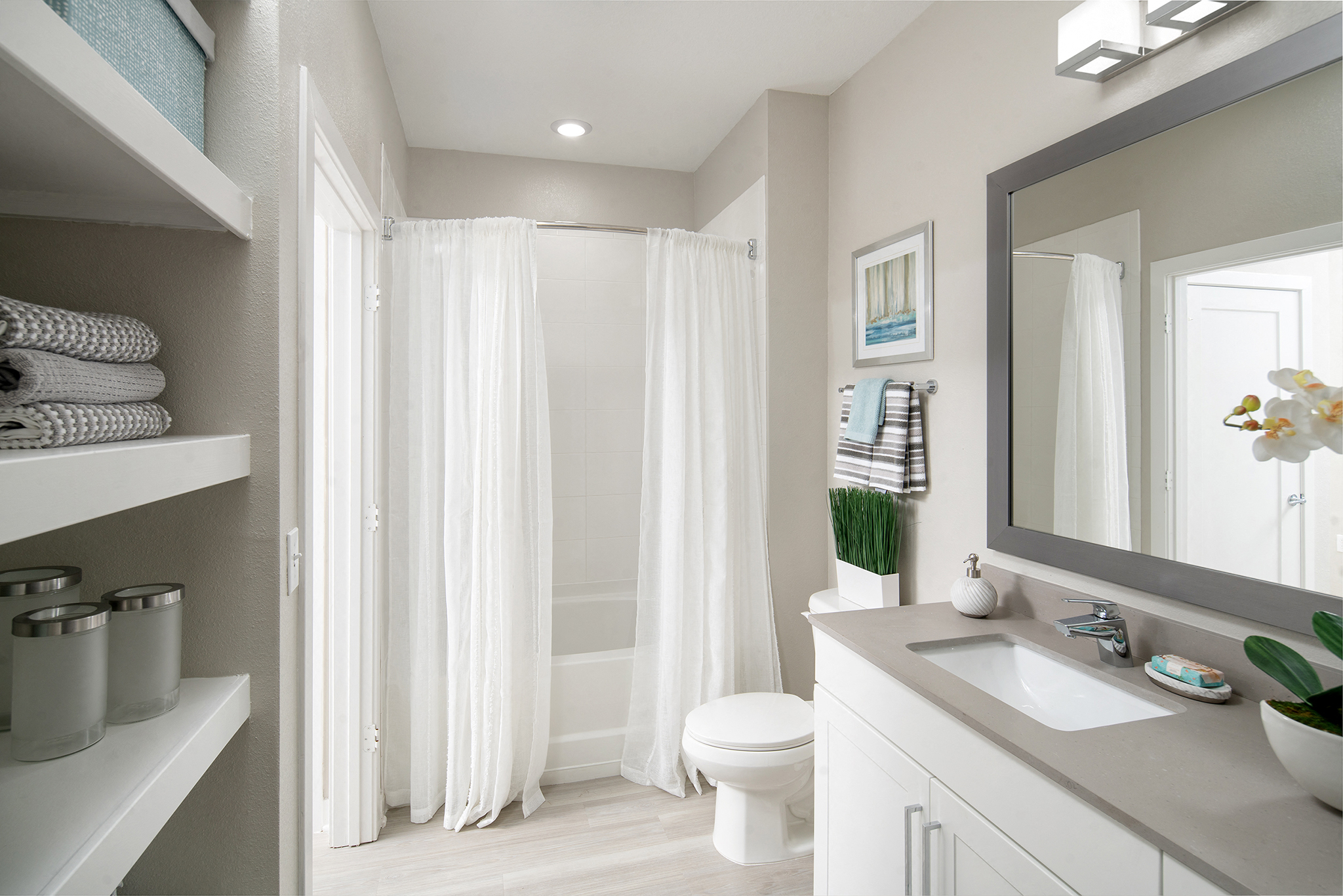 Bainbridge Westshore Marina Bathroom with Gray Quartz Countertop, Framed Mirror, Open Linen Closet, and Shower Tub Combo with Curved Shower Rod