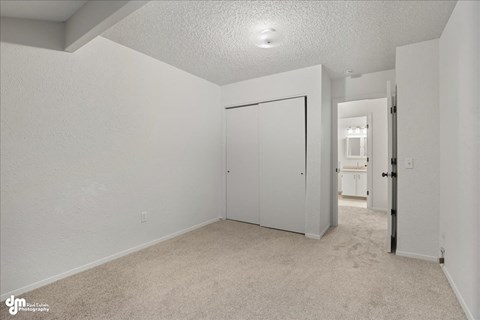 A white bedroom with a carpeted floor and a white door.