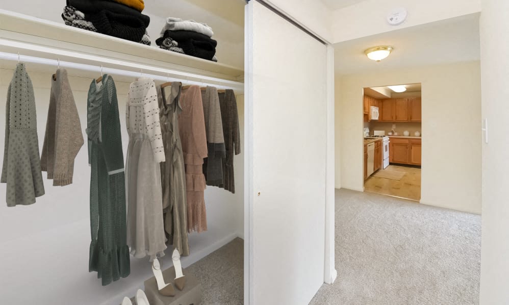 a walk in closet with clothes hanging on a rack