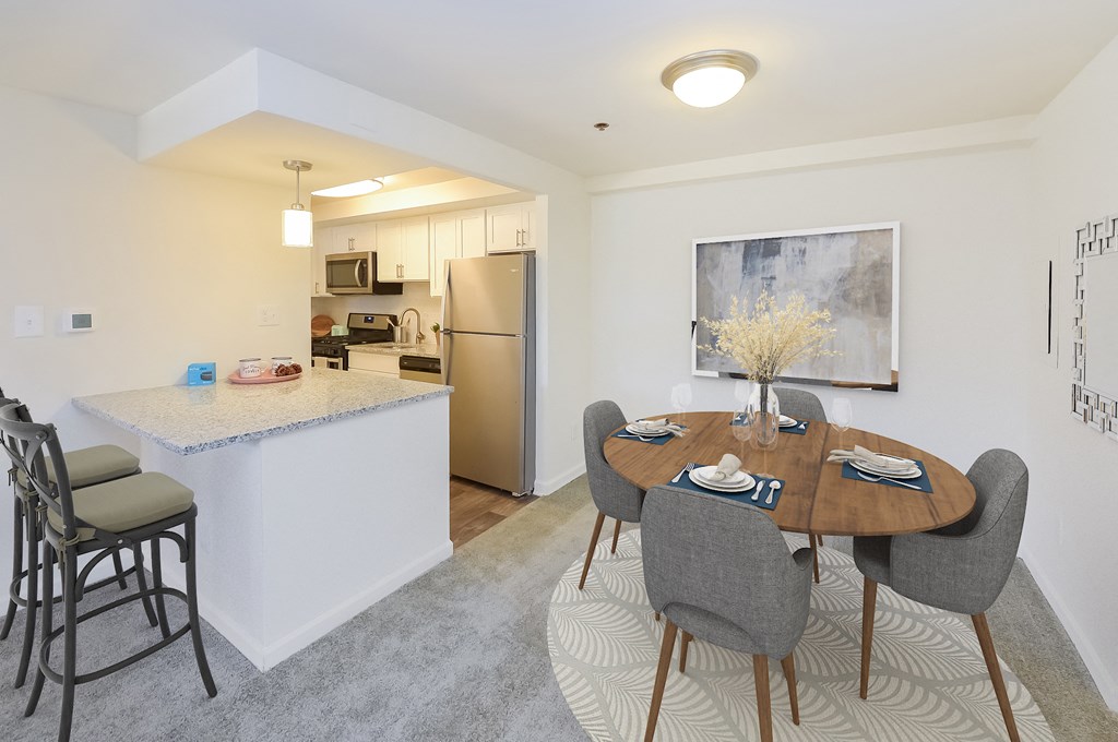 a dining area with a table and chairs and a kitchen with stainless steel appliances