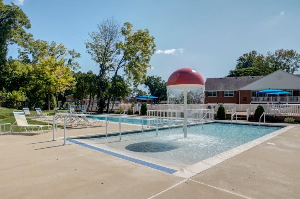 a pool with a water fountain and a building in the background