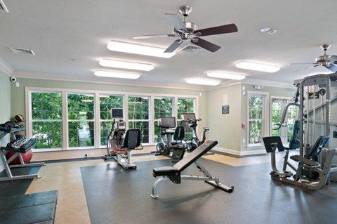 a gym with several machines and a ceiling fan