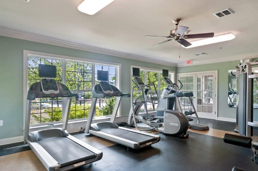 a gym with cardio machines and a ceiling fan