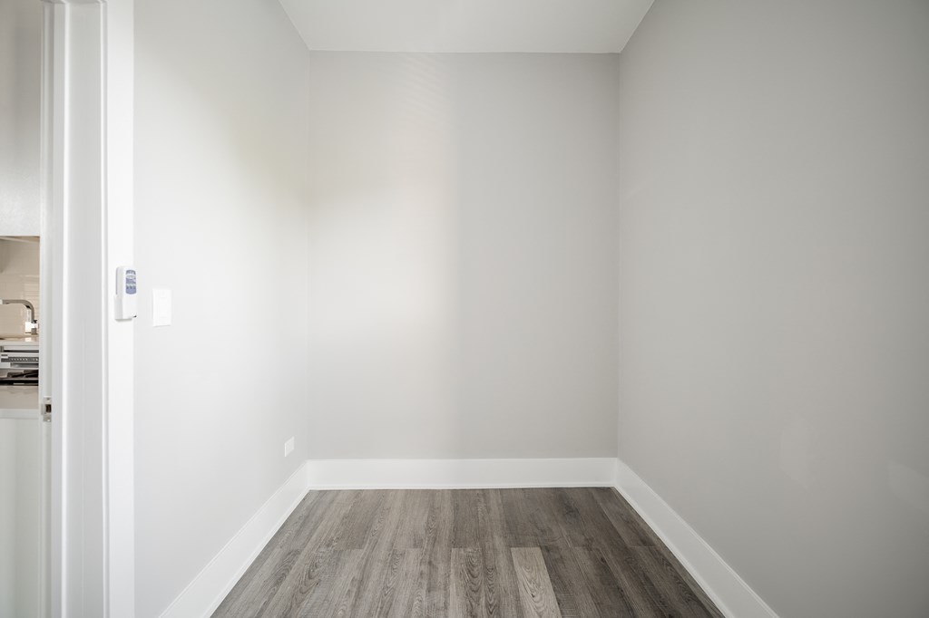 an empty room with white walls and wood floors