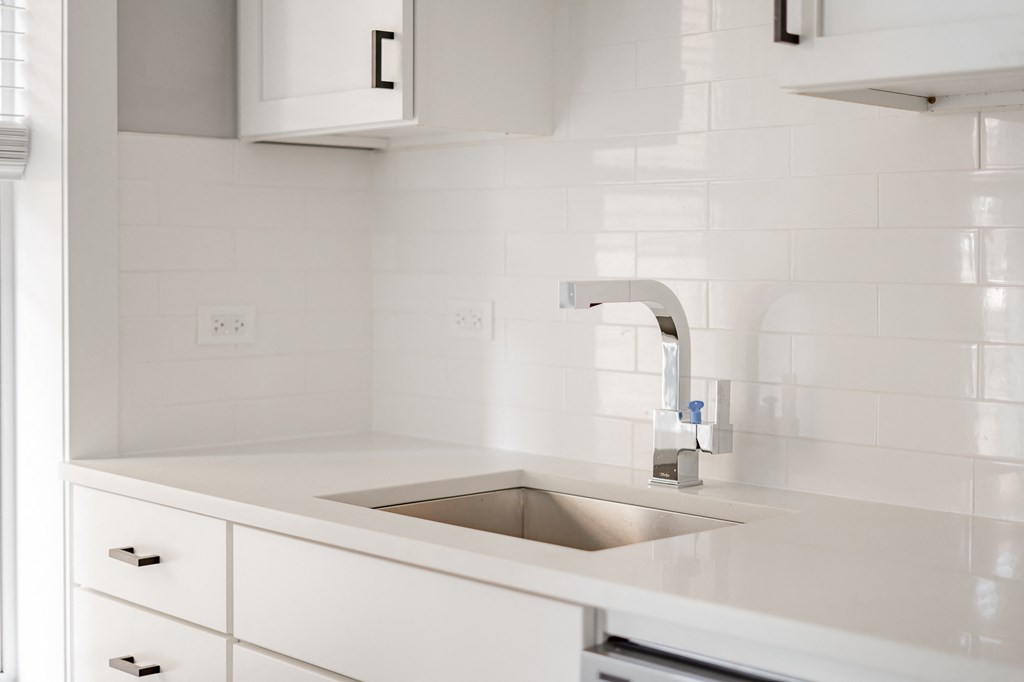 a white kitchen with a sink and white cabinets