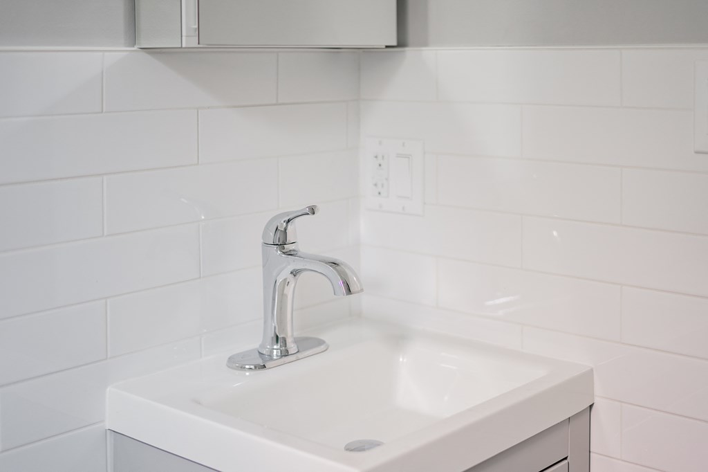 a white sink in a bathroom with a silver faucet