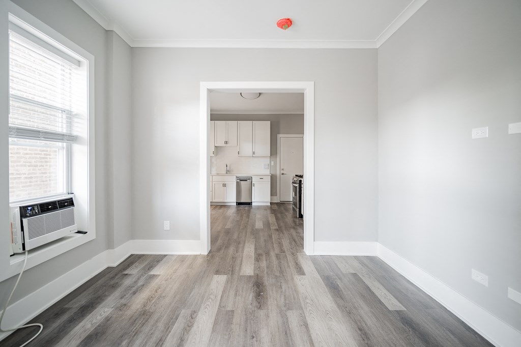 a living room and kitchen with white walls and wood flooring