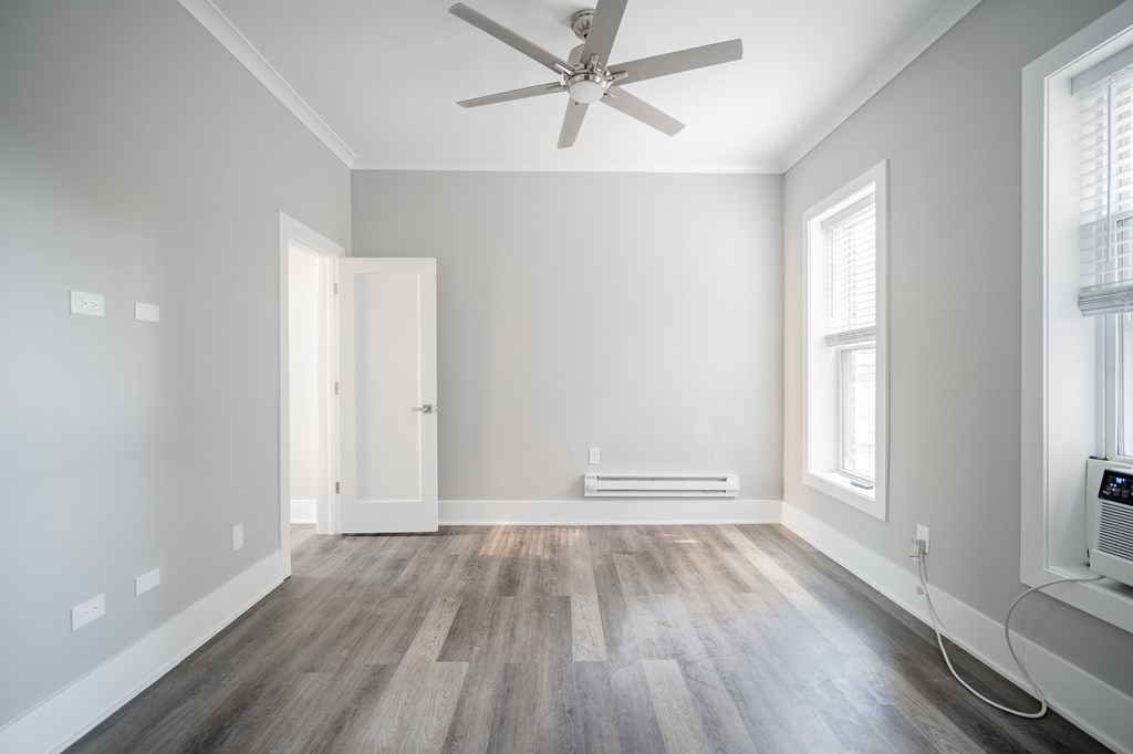 an empty living room with wood floors and a ceiling fan
