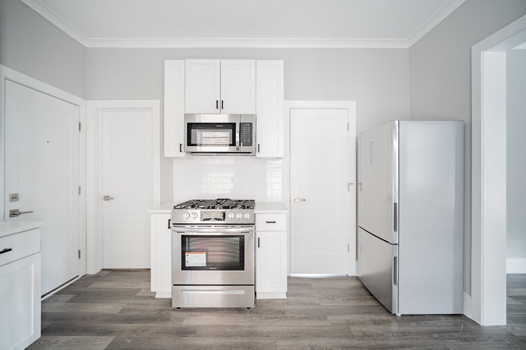 a white kitchen with stainless steel appliances and white cabinets