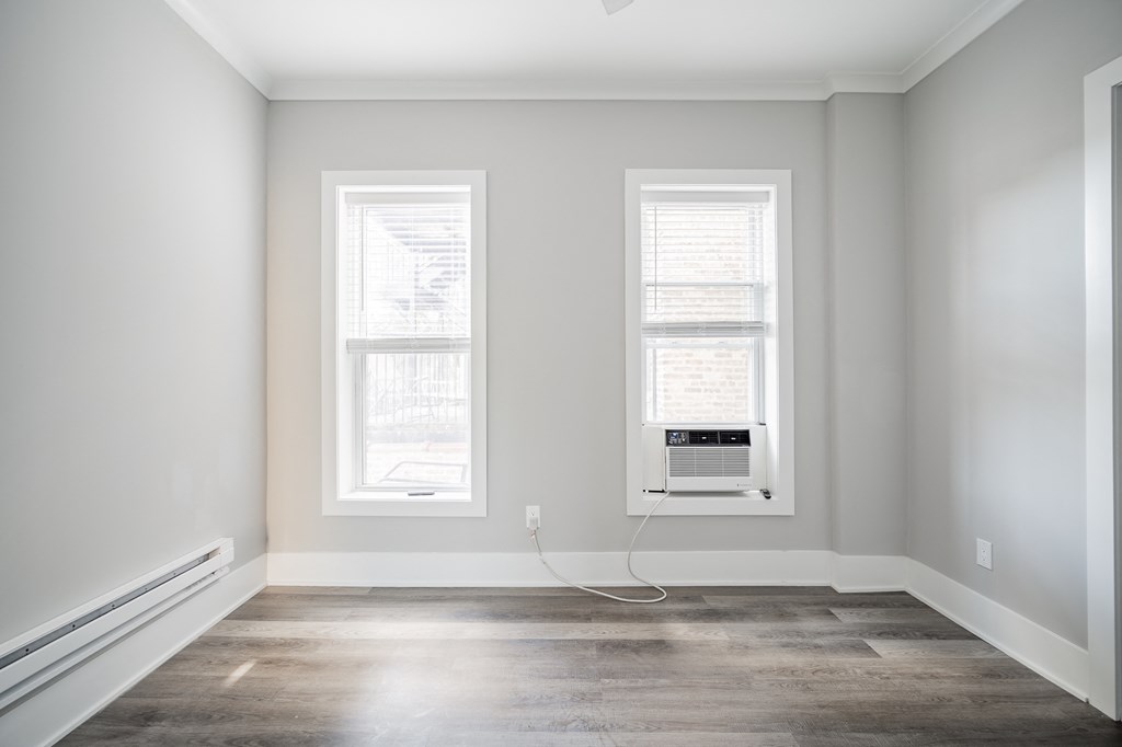 an empty room with two windows and a air conditioner in it