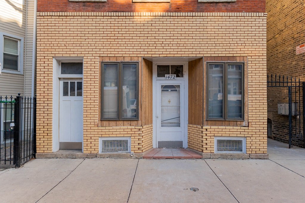 the front of a brick building with two doors and a sidewalk