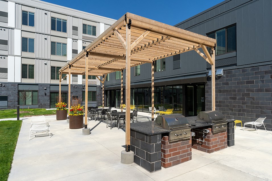 an outdoor patio with a barbecue grill and tables and chairs