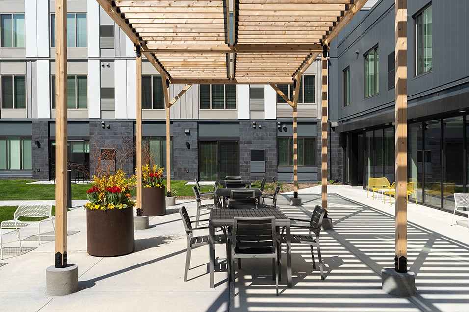 a patio area with tables and chairs under a wooden canopy