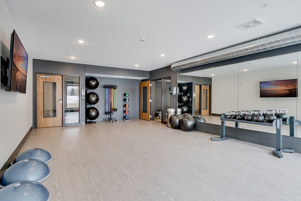 a workout room with weights on the floor and a large mirror