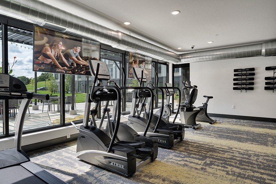 a gym with cardio machines and windows in a building