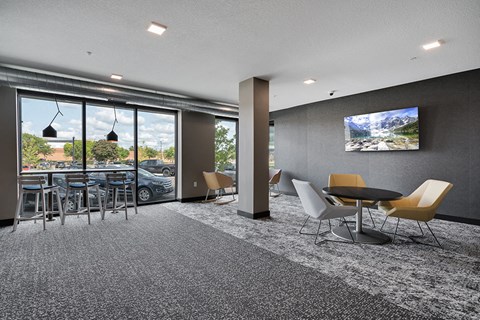 a lounge area with tables and chairs and a television on the wall