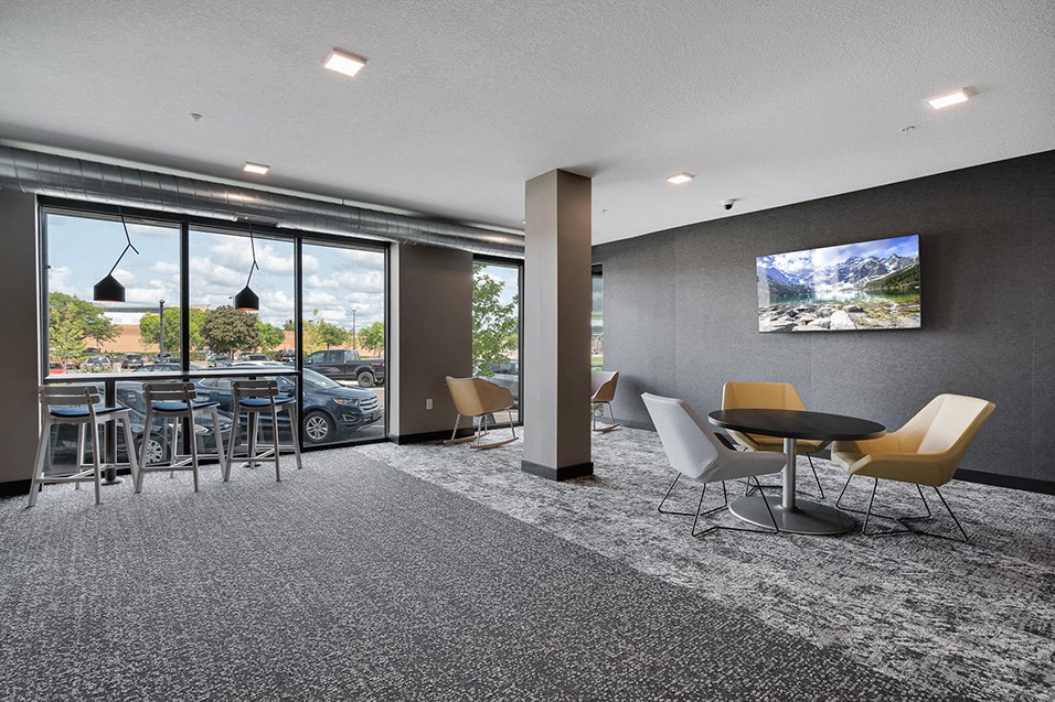 a lounge area with tables and chairs and a television on the wall