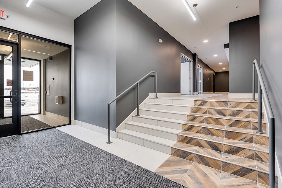 the lobby of a building with stairs and glass doors