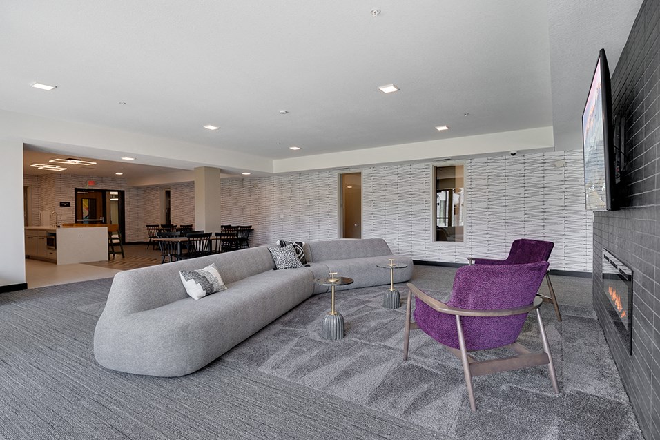 a living room with a gray couch and purple chairs