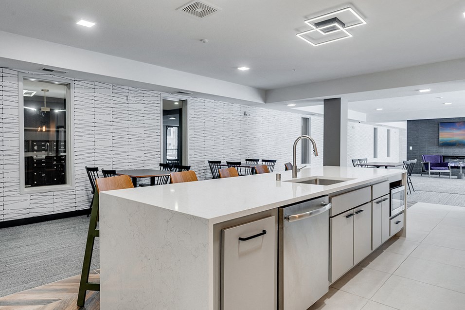 a large kitchen with an island and a dining room with chairs