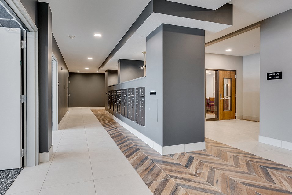 the lobby of a building with a long hallway with grey walls and a tile floor