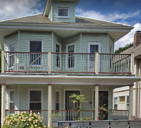 a green house with a balcony on top of it