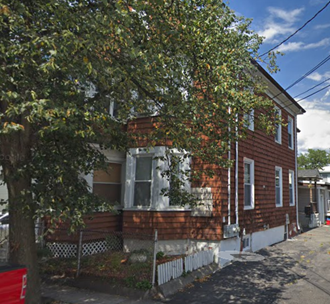 a red brick house with a tree in front of it