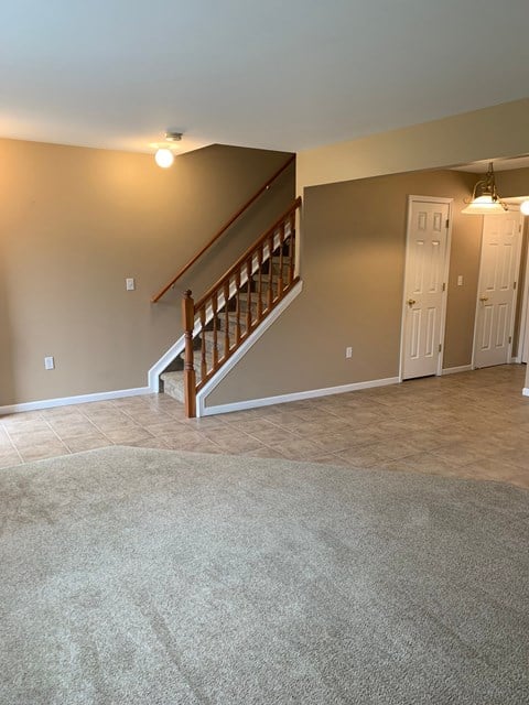 a living room with a staircase and a carpet floor