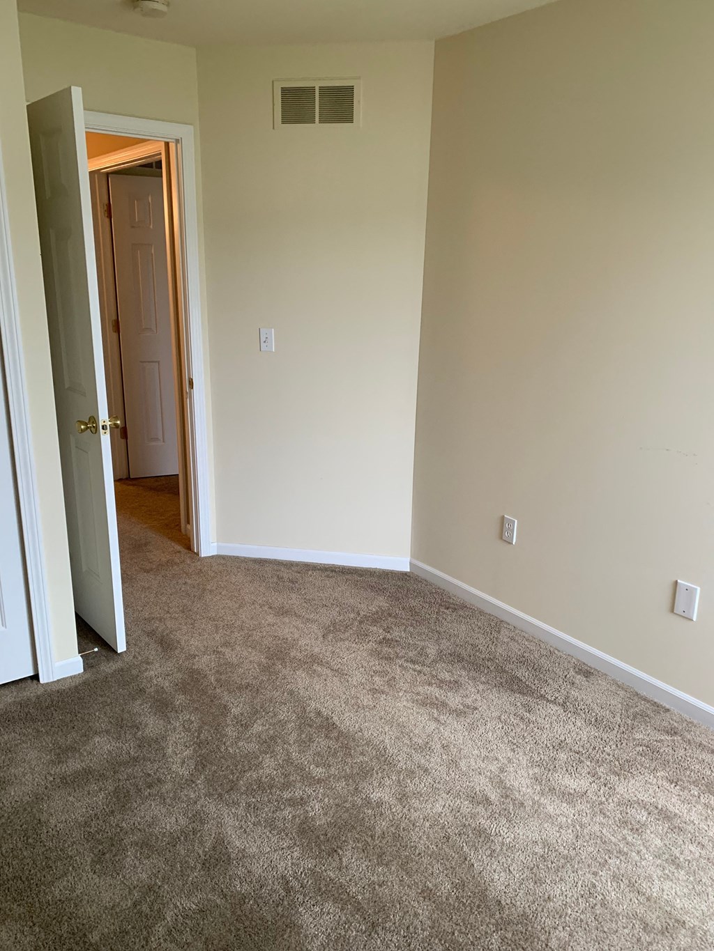 a room with a carpeted floor and a door to a hallway