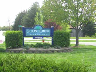 the sign apartments is in front of a lawn and trees