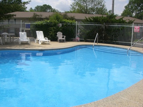 a large pool with chairs and a fence around it