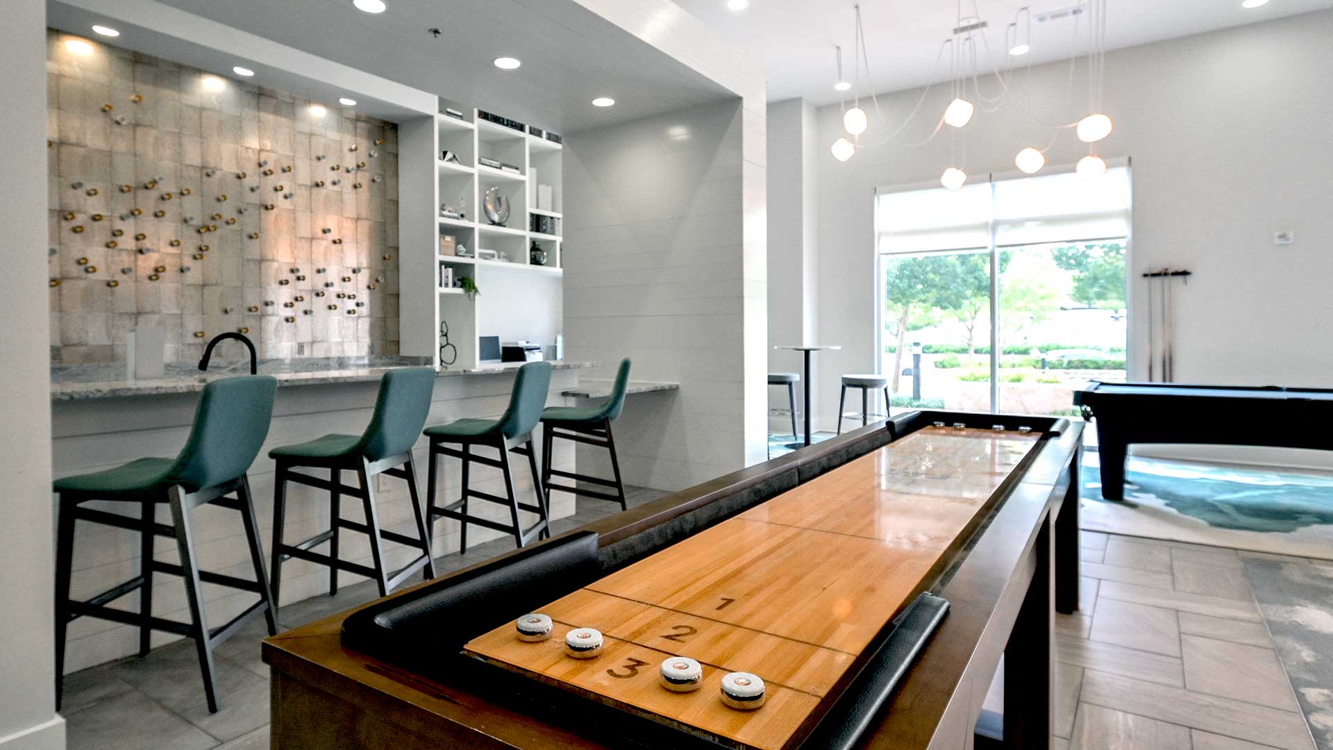 Looking down along a shuffle board table in the lounge. A bar in on the left with a pool table further back on the right.