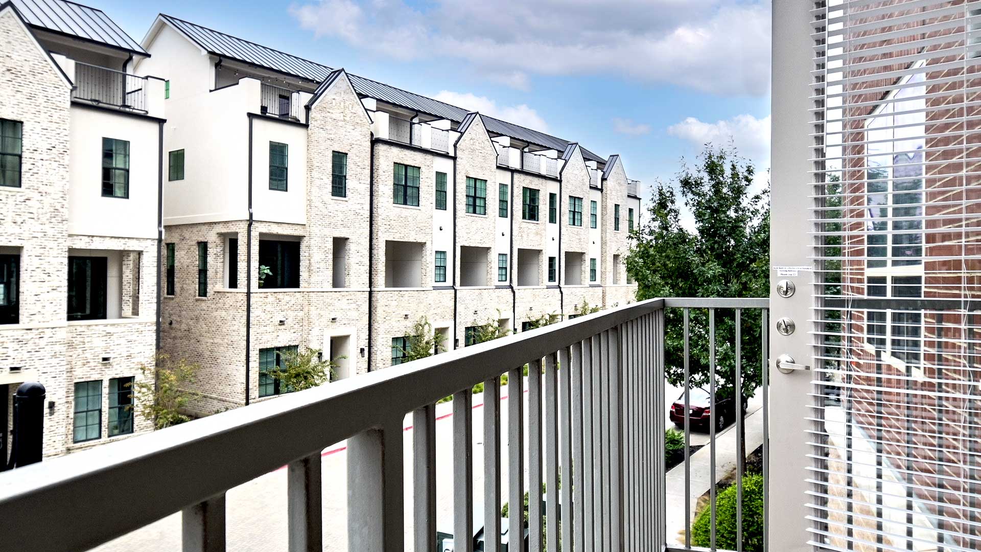 Standing on a balcony looking out at neighboring buildings on a partly cloudy day.